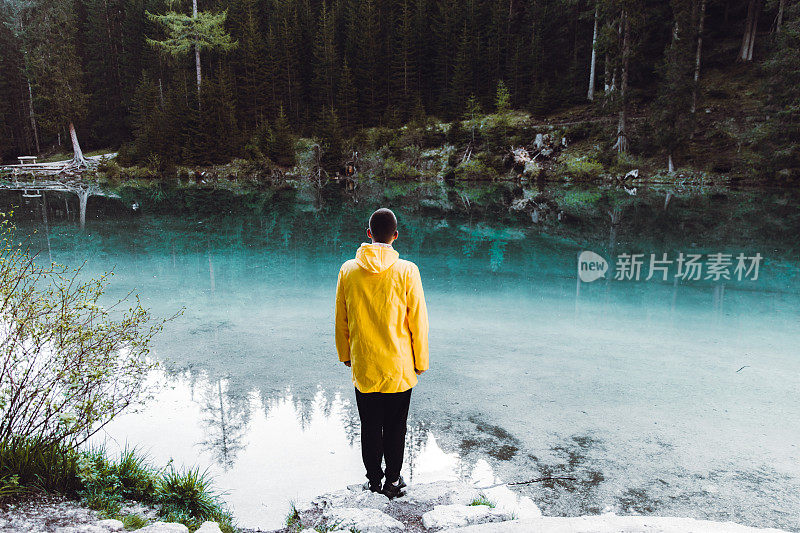 身穿雨衣的男子在Dolomites阿尔卑斯山的Lago Di braes享受日出